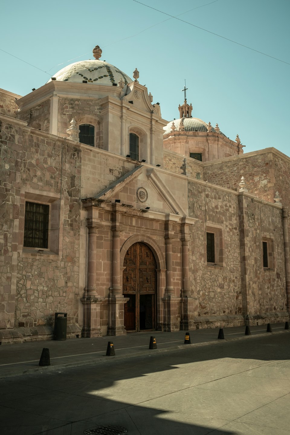 Grand stone church with ornate wooden doors under a clear sky.